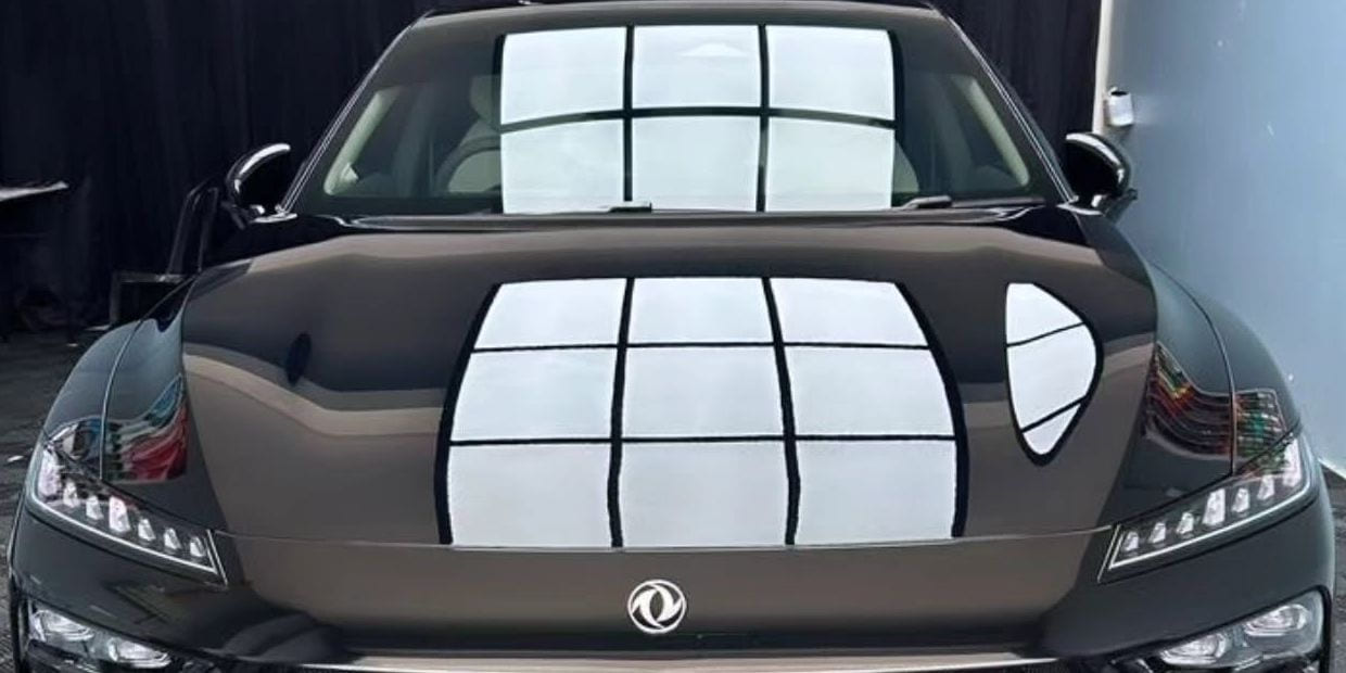 The ceiling light panel reflected as a straight rectangular grid across the bonnet and windscreen of a black Dongfeng sedan.